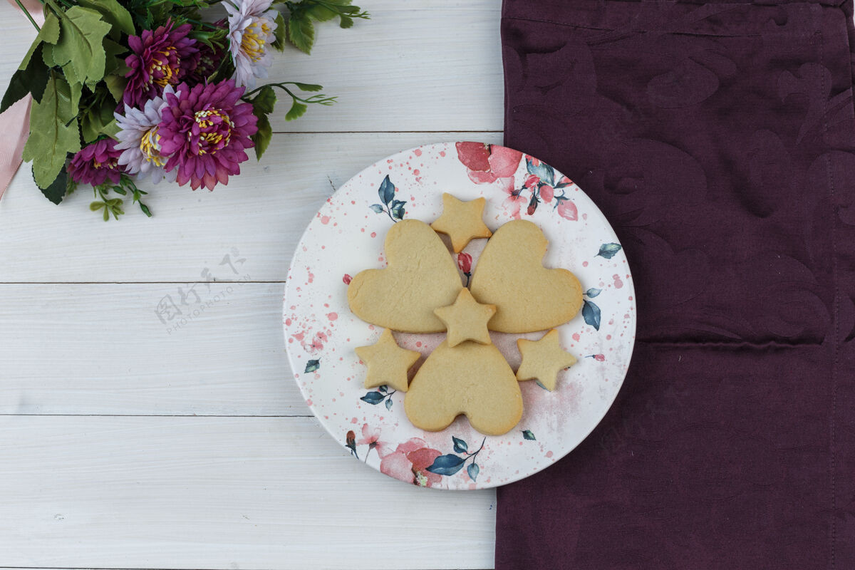 食物饼干放在一个有花的盘子里平放在木制和纺织品的背景上糖美味饼干