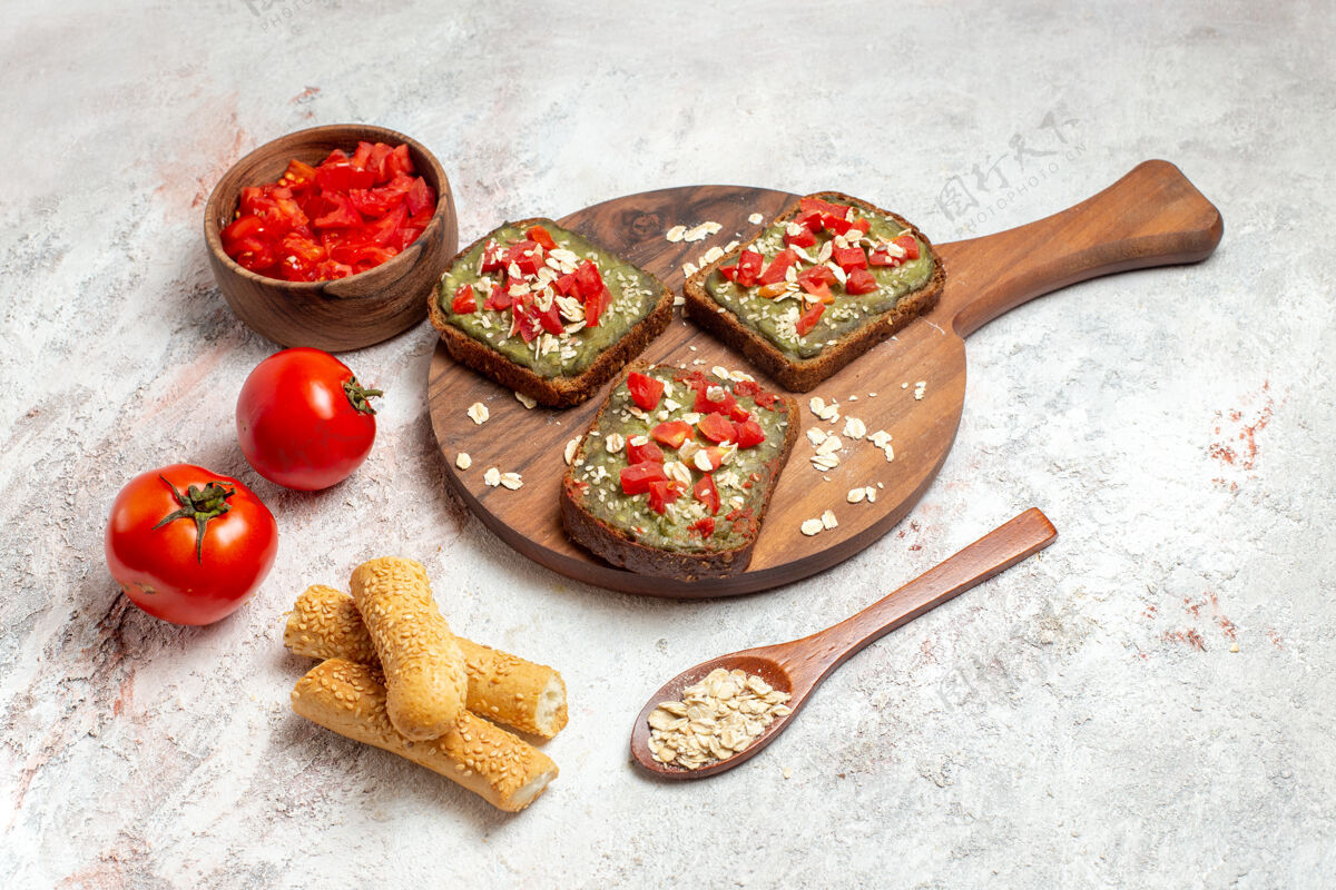 新鲜前视图美味的鳄梨三明治和新鲜的红色西红柿在白色空间胡椒粉西红柿前面