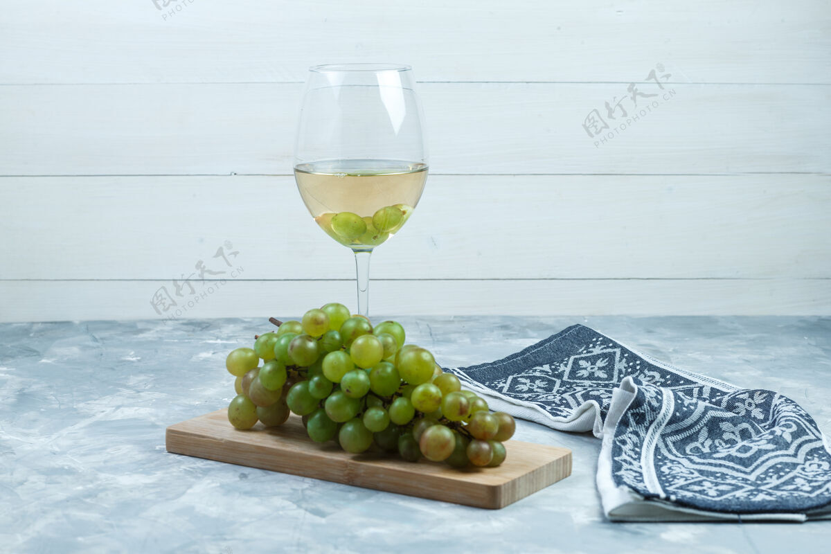 树枝侧视图绿色葡萄与一杯葡萄酒 木片 厨房毛巾在木制和肮脏的灰色背景水平咕噜咕噜夏天葡萄