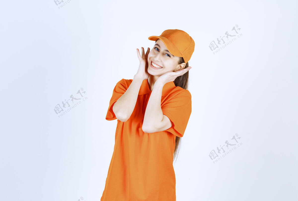 模特女信使穿着橙色制服 戴着帽子聪明服装姿势