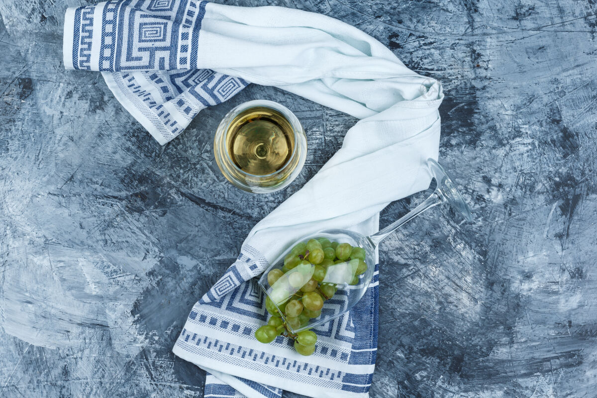 葡萄酒平放一杯白葡萄和一杯威士忌 厨房毛巾放在深蓝色大理石背景上水平葡萄水平多汁的
