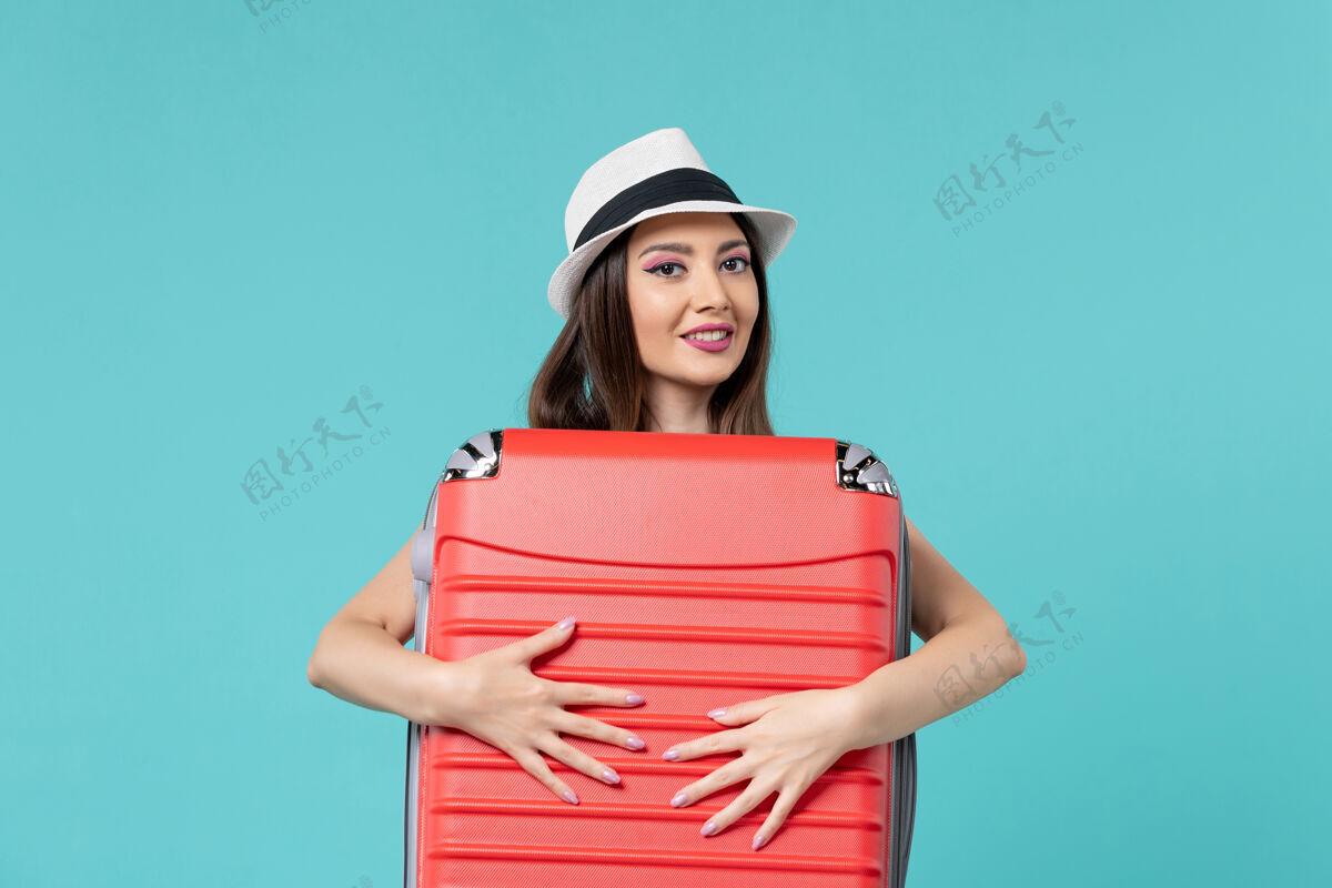 女性前视图美丽的女性手持红色袋子 准备在浅蓝色空间旅行美丽的女性袋子海