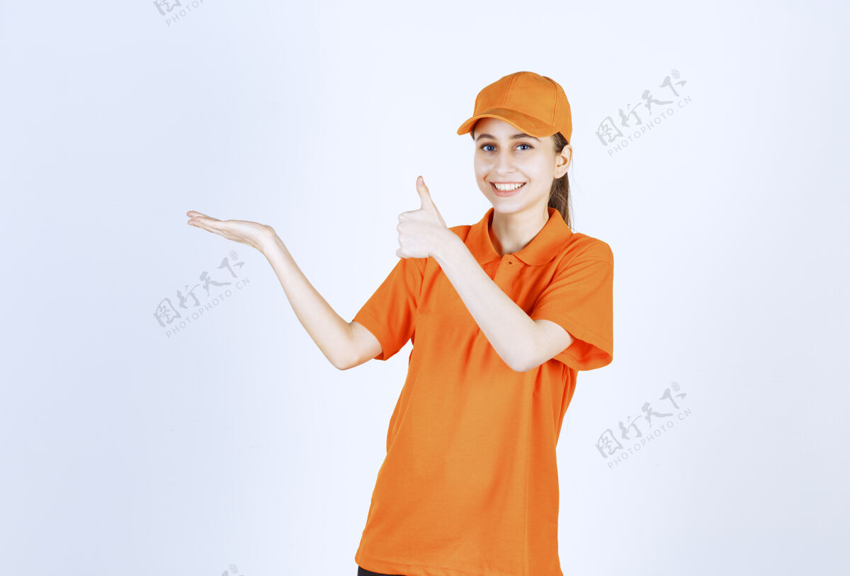 休闲女信使穿着橙色制服 戴着帽子 大拇指朝上运输好送货