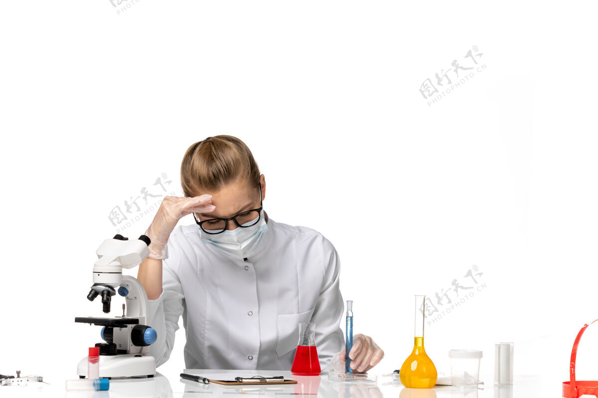 前台正面图：女医生穿着医疗服 戴着面罩 因为科维德在白色办公桌上用溶液工作到期套装办公桌