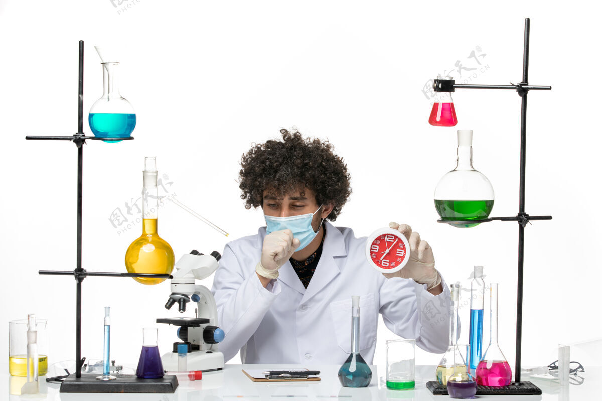 男性化学家正面图：男药剂师穿着医疗服 戴着面罩 拿着红色的时钟 在空白处咳嗽男性化学医学