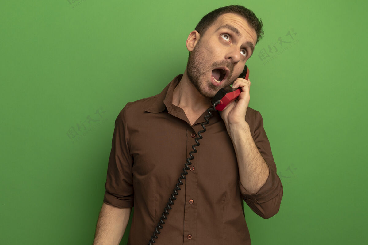 电话令人印象深刻的年轻白种人仰望电话交谈隔离在绿色的墙壁与复制空间年轻人印象男人