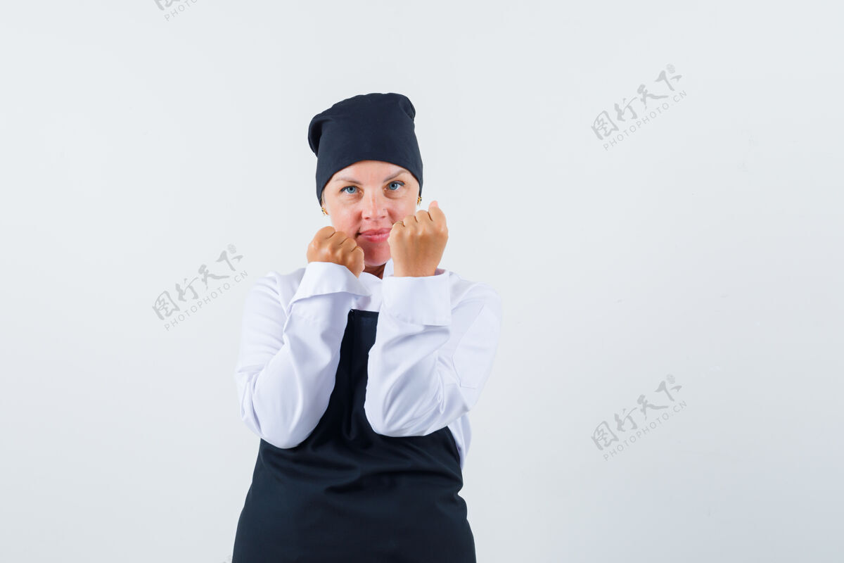 欢呼女厨师穿着制服 围着围裙站在战斗姿势 看起来很自信前视图站立围裙肖像