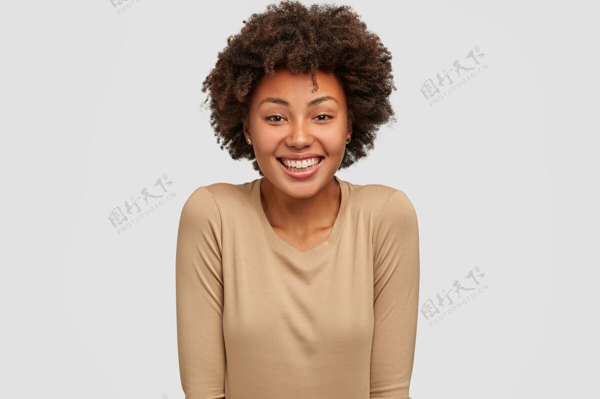 个体笑容可掬的黑皮肤女人留着非洲式发型镜头凝视欣喜若狂
