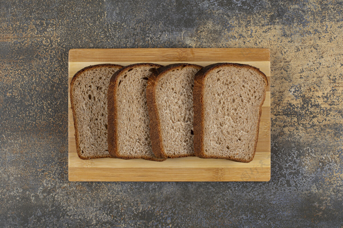 面包把新鲜黑麦面包片放在木板上小块小吃烘焙