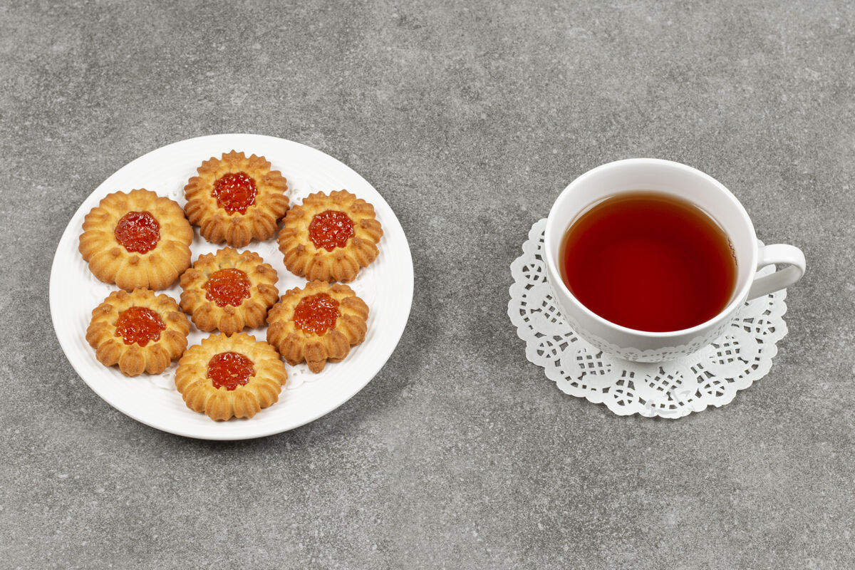 茶在大理石表面放一盘果冻饼干和一杯茶甜点面包店饼干