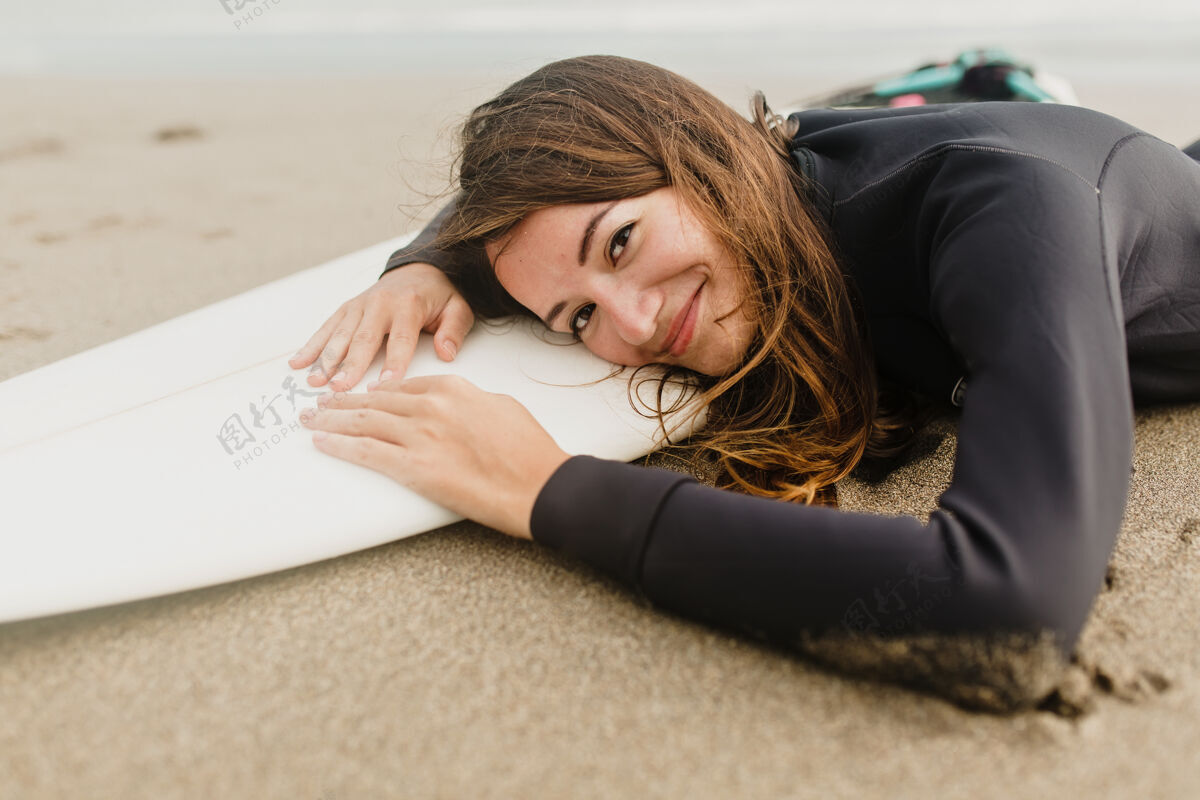 阳光在阳光明媚温暖的日子里 穿着潜水服躺在沙滩冲浪板上的迷人女人爱好阳光水平
