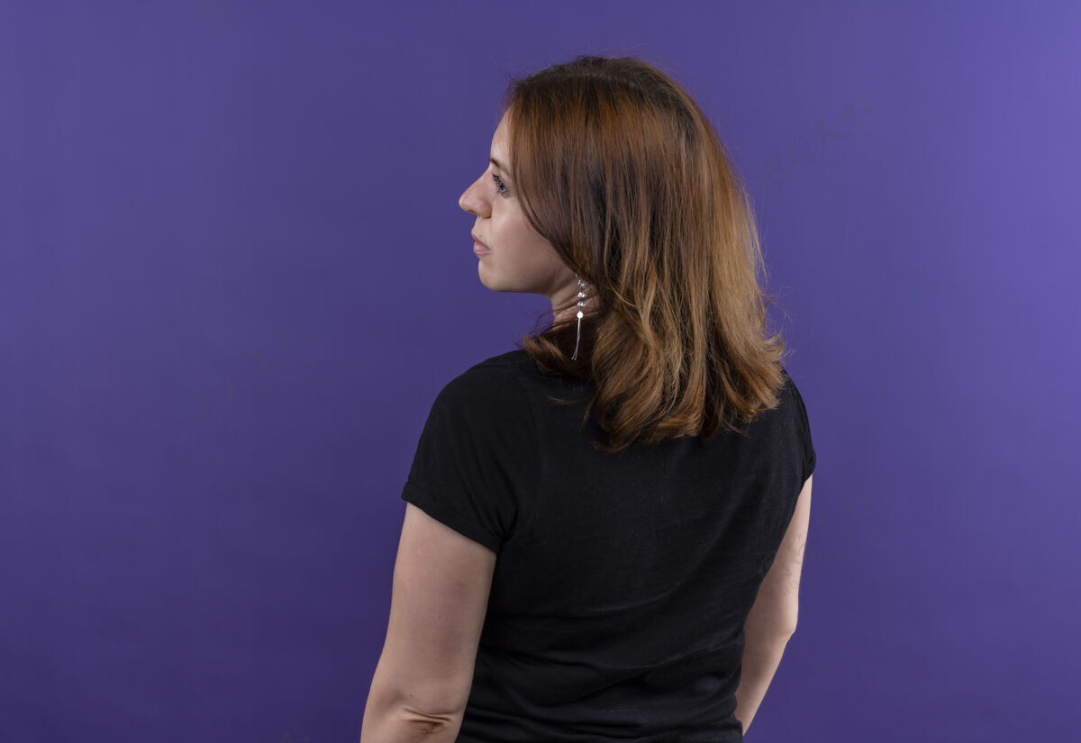 女人年轻随意的女人站在后面的视野里 看着左边孤立的紫色墙壁上的复制空间站立女孩侧线