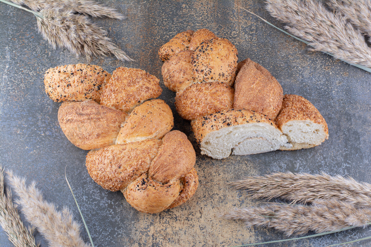 谷物切成片的斯特拉西亚面包和一捆麦秆放在大理石表面面包外套切片