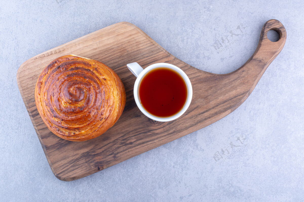 馒头在大理石表面的木板上放一杯茶和一个甜面包杯烘焙食品美味