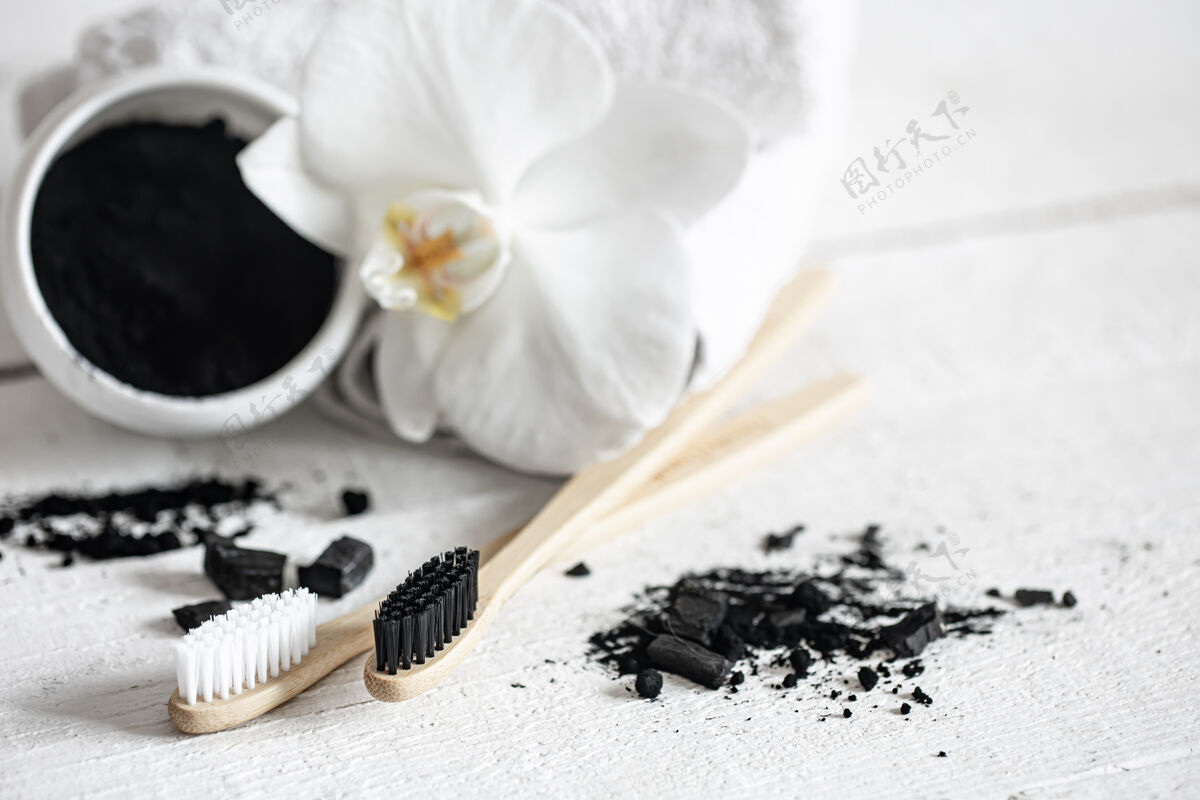 黑色用木质天然牙刷组成 黑色牙齿美白粉和兰花复制空间自然牙齿复制空间