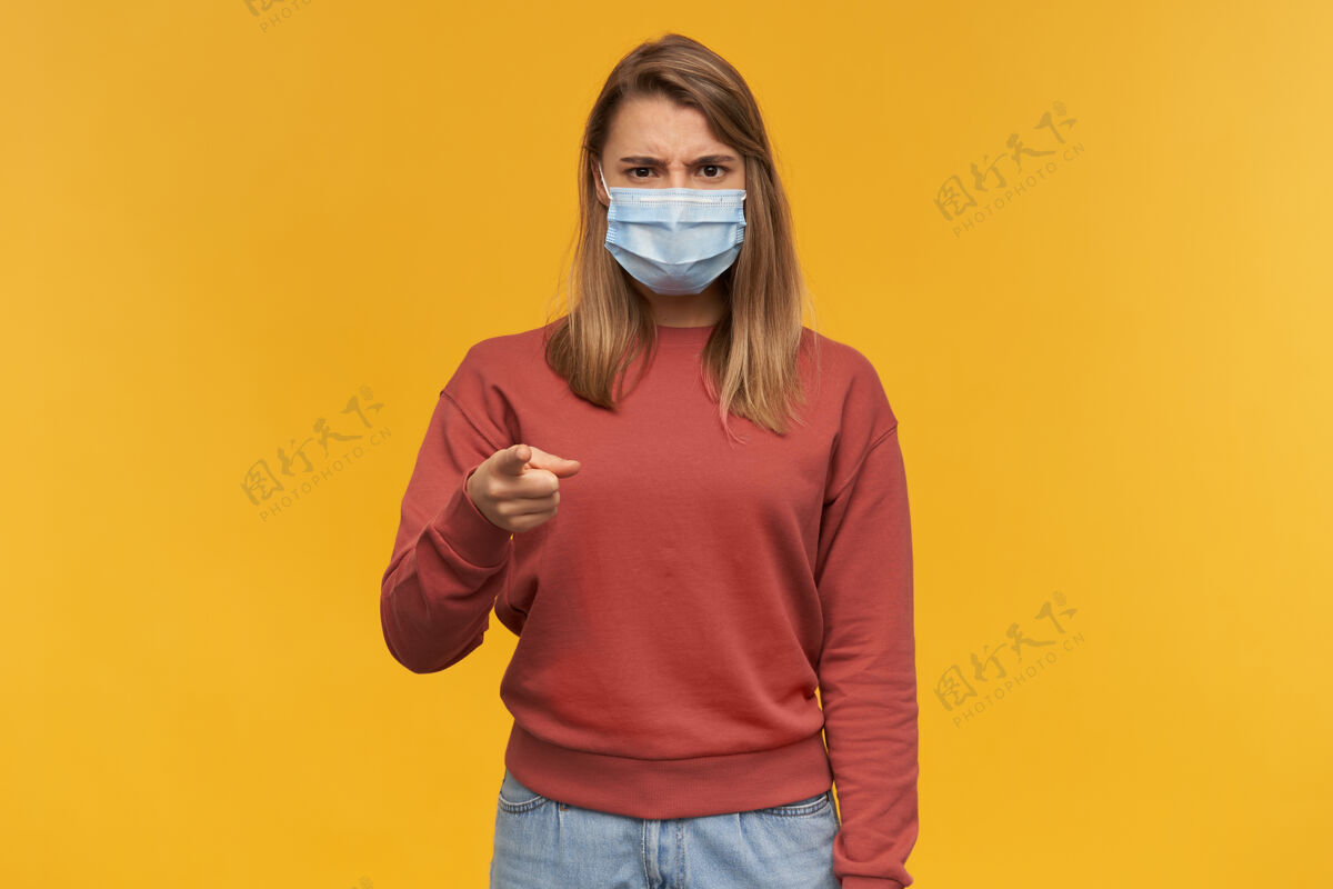 指向疯狂刺激的年轻女性在医疗保护中感冒感冒面罩 指着黄墙上的你成人青少年女性