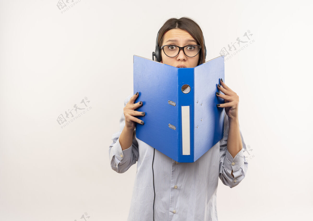 手持印象深刻的年轻呼叫中心女孩戴着眼镜和耳机举行 并从后面看文件夹上白色的副本空间隔离眼镜文件夹呼叫
