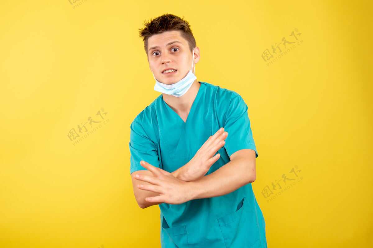 绝育正面图身着医疗服的年轻男医生 黄色背景上有无菌面罩医学面具肖像