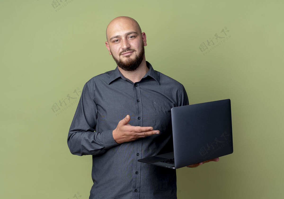 电话自信的年轻秃头呼叫中心男子手拿笔记本电脑指着橄榄绿的复印空间复制人中心