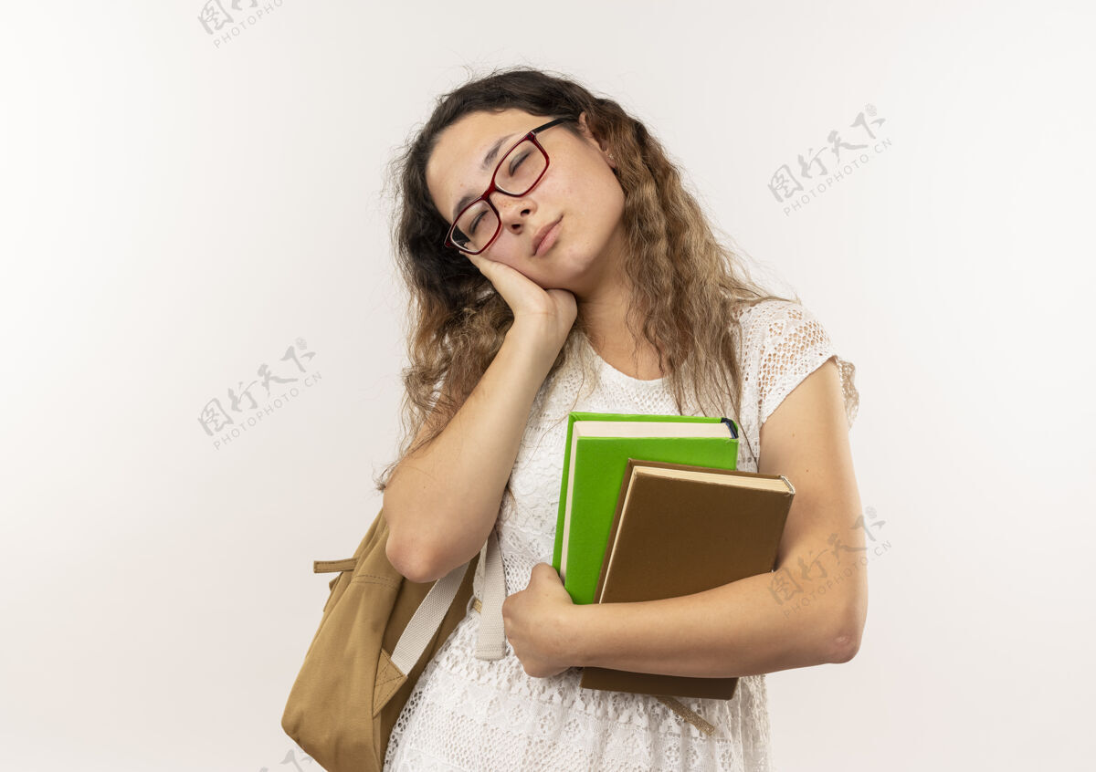 穿梦幻般的年轻漂亮的女学生戴着眼镜 背着书包 做着睡觉的姿势 隔离在白色的空白处漂亮女学生年轻