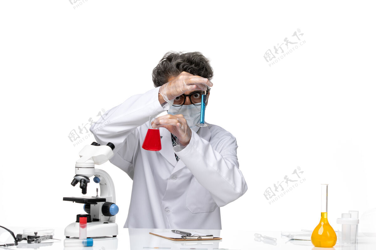 男性正面图穿着特殊套装的中年科学家坐着拿着装有解决方案的烧瓶化学观点前面