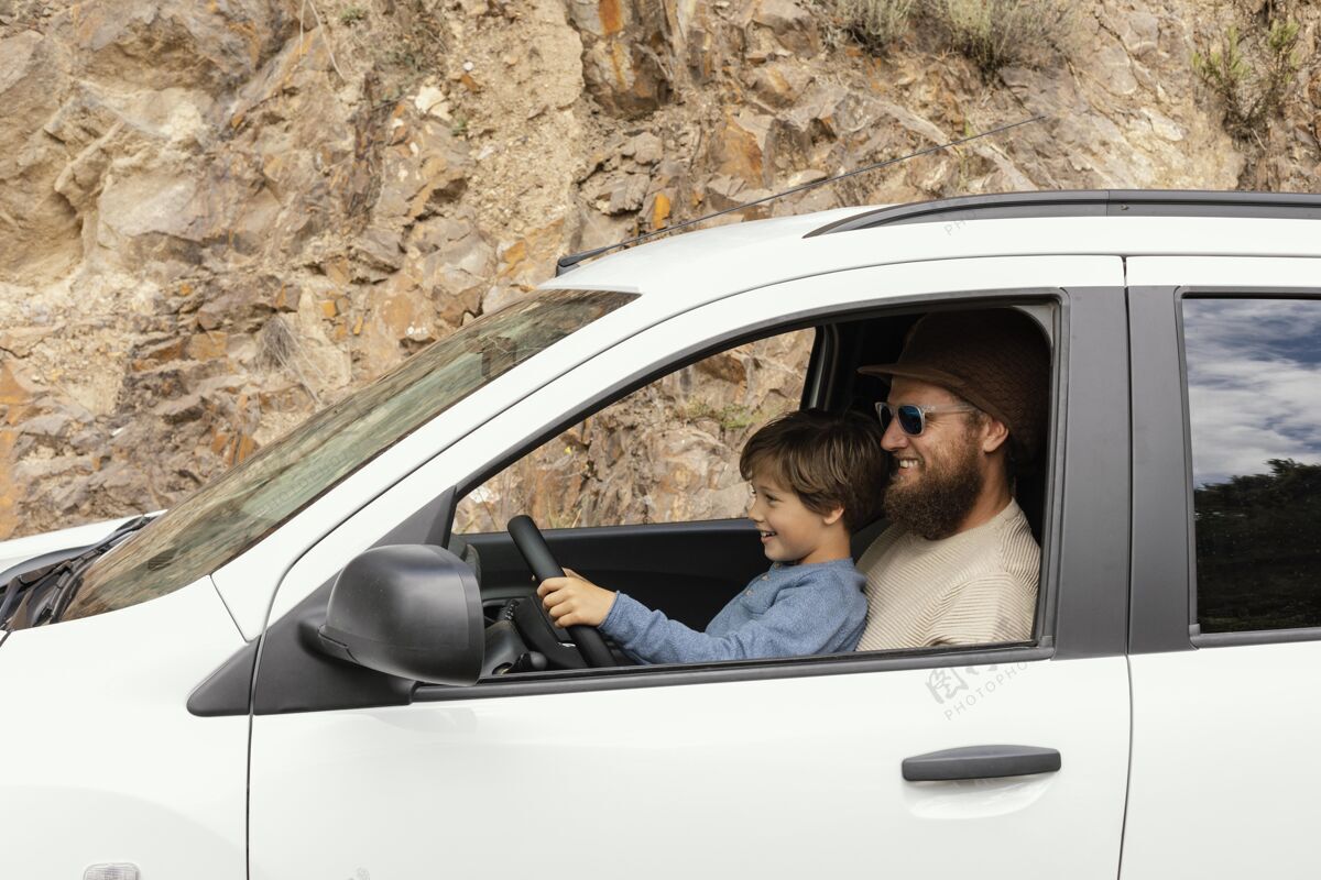 男孩侧视图父亲和儿子在圈内驾驶探索汽车旅行