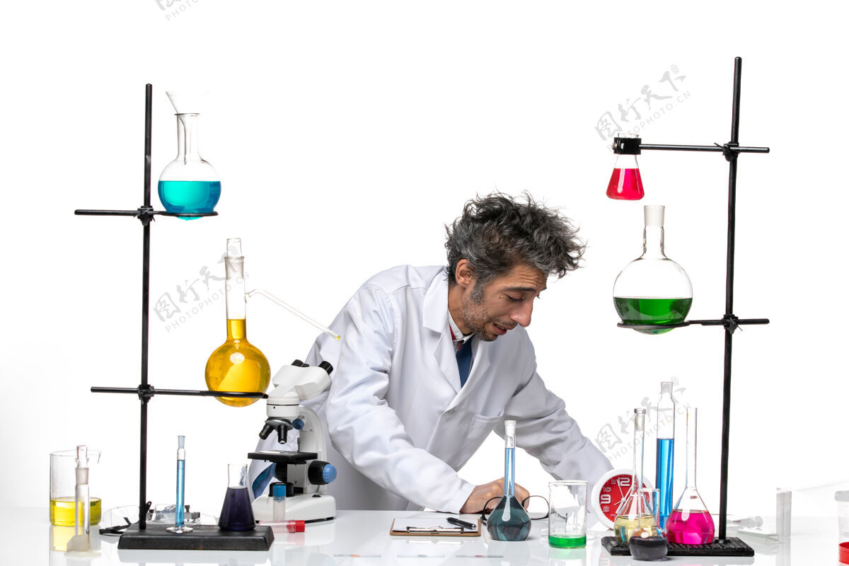 实验室前视图穿着白色医疗服的男科学家在桌子前拿着解决方案技术人员工作医学