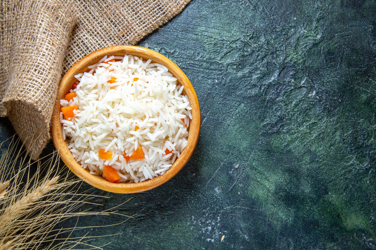 食物在黑暗的桌子上的小盘子里俯瞰美味的煮米饭蔬菜晚餐午餐