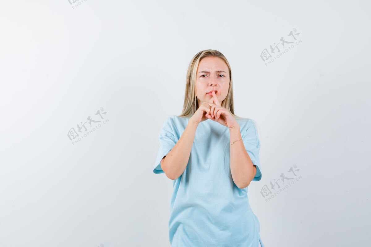 时尚穿着t恤的年轻女士 手指放在嘴上 表情严肃 正面照成人皮肤护理健康