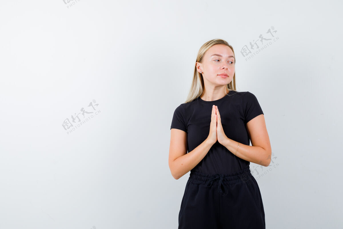 销售年轻女士手牵手祈祷的姿势在t恤衫 裤子和期待前视图前面皮肤女性