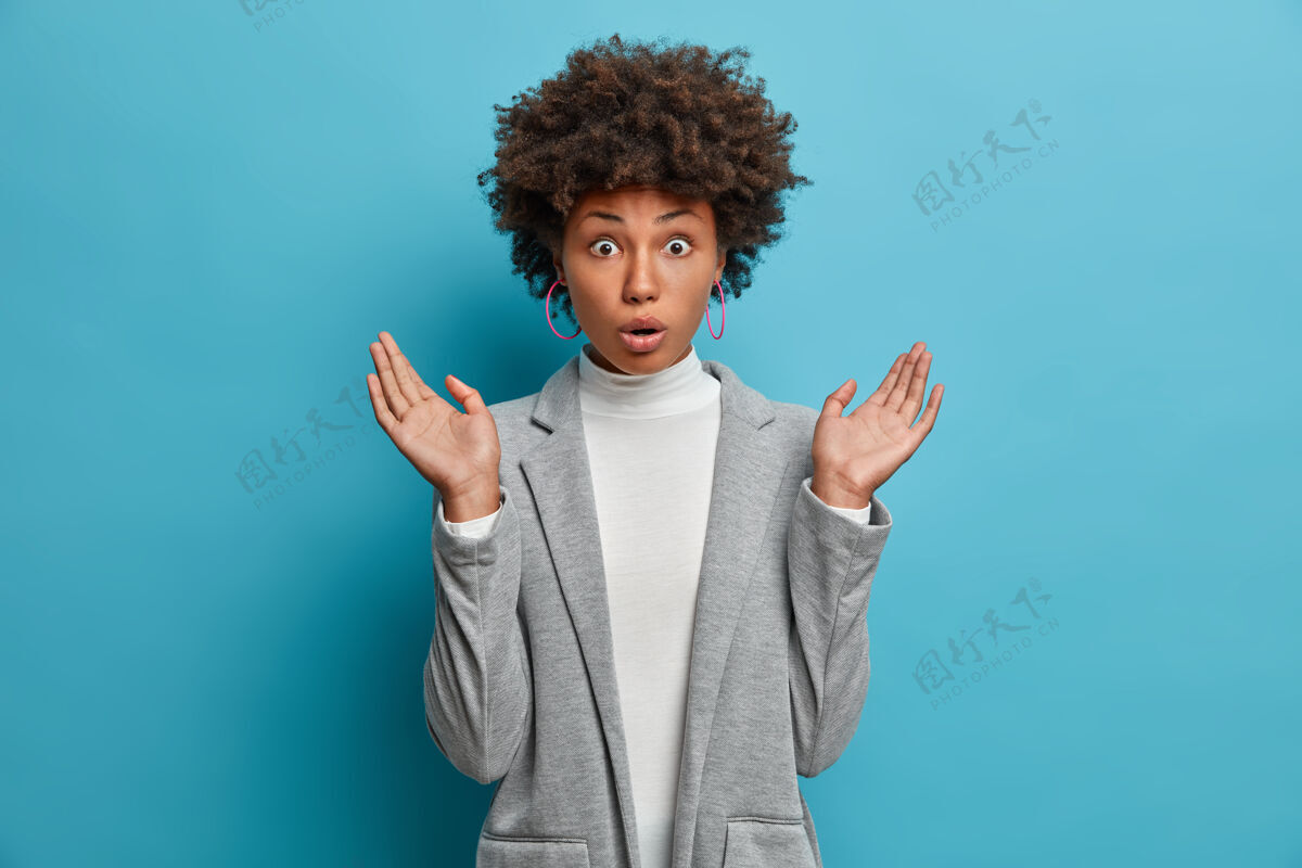 年轻惊愕的黑皮肤女人摊开手掌 对惊骇的消息做出反应 意识到她忘记了重要的任务 穿着优雅的灰色夹克表情无语惊奇