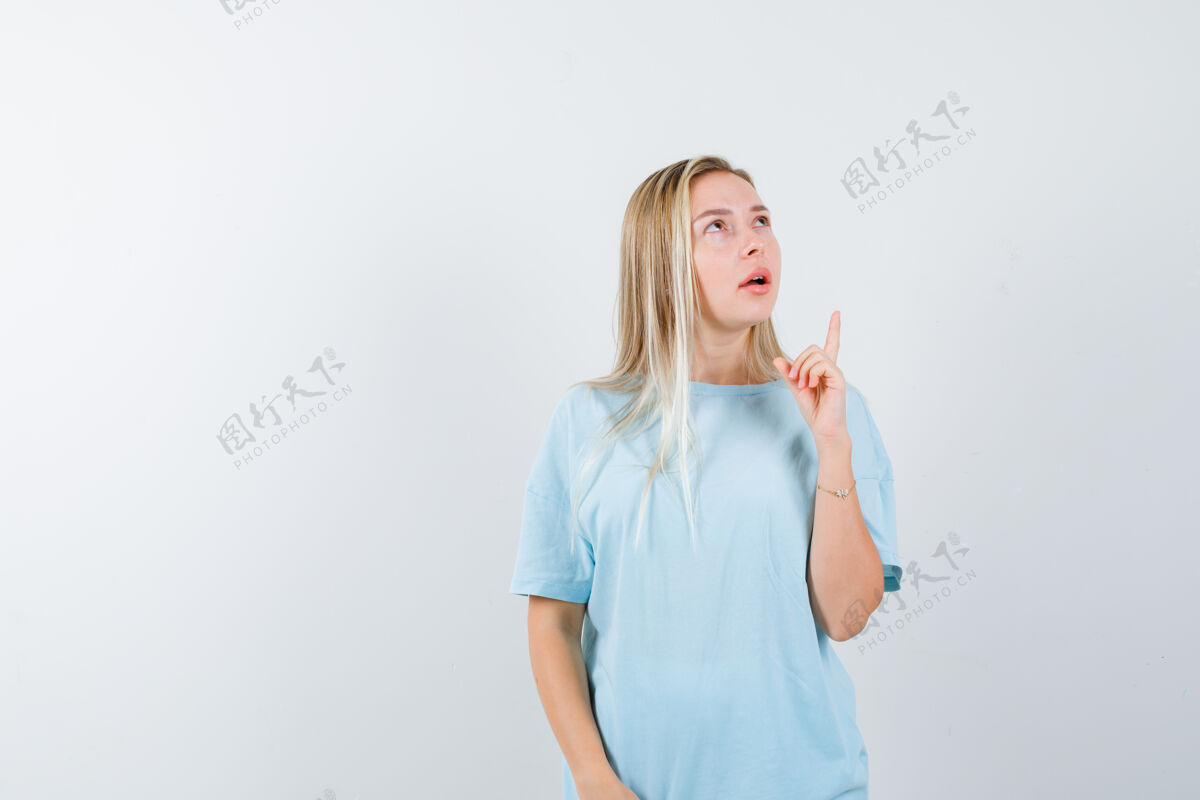 女性穿着蓝色t恤的金发女孩用食指向上指 向上看 神情沉思 俯视前方人天空手指