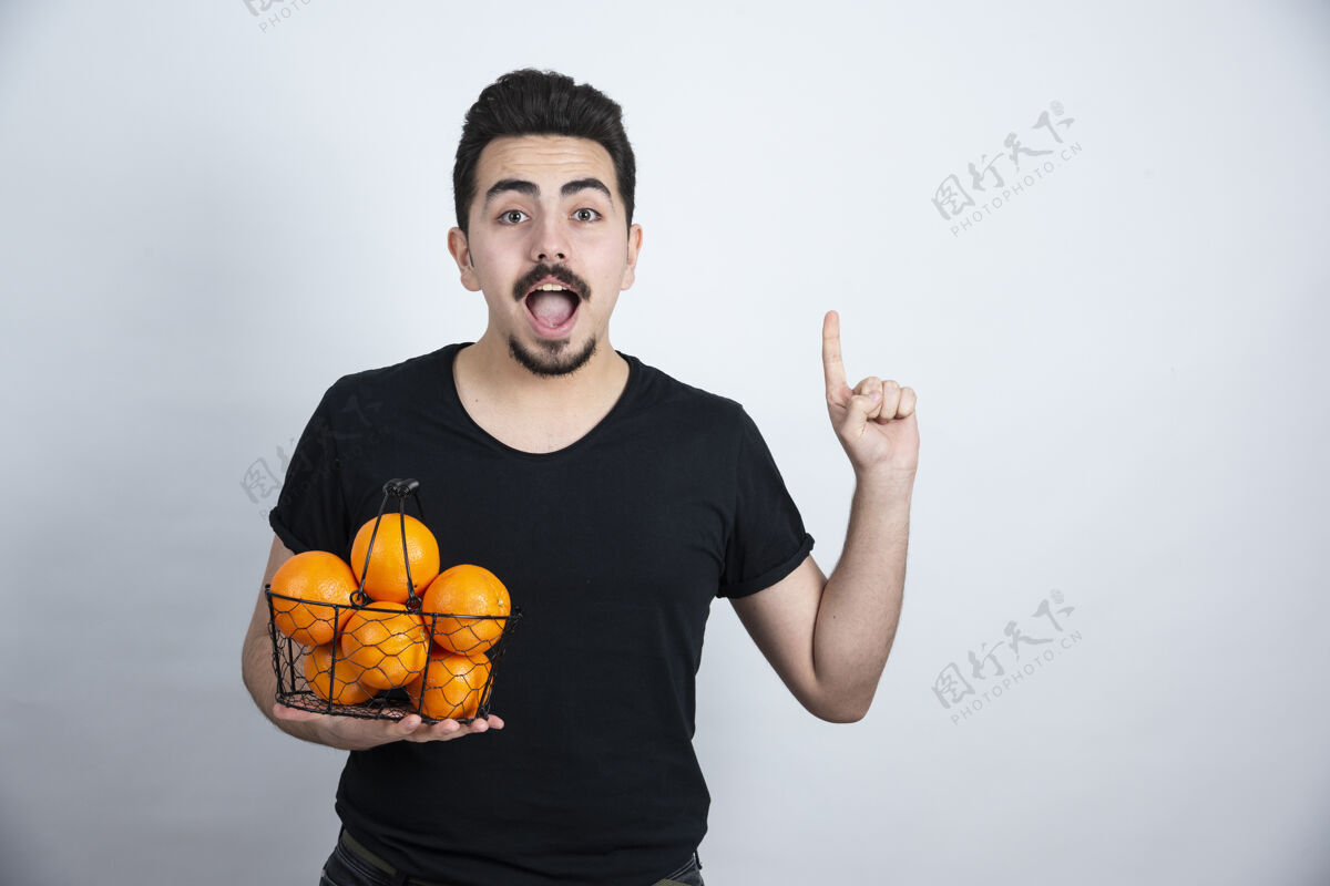 时尚一个年轻人 手里拿着装满橘子的金属篮子篮子人人类