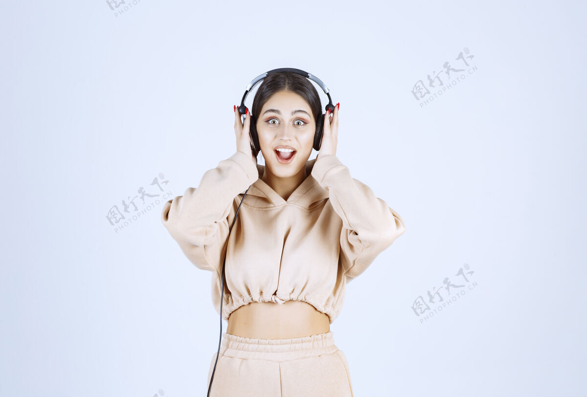 乐趣年轻女子戴着耳机 愉快地听着她的播放列表人女人女性