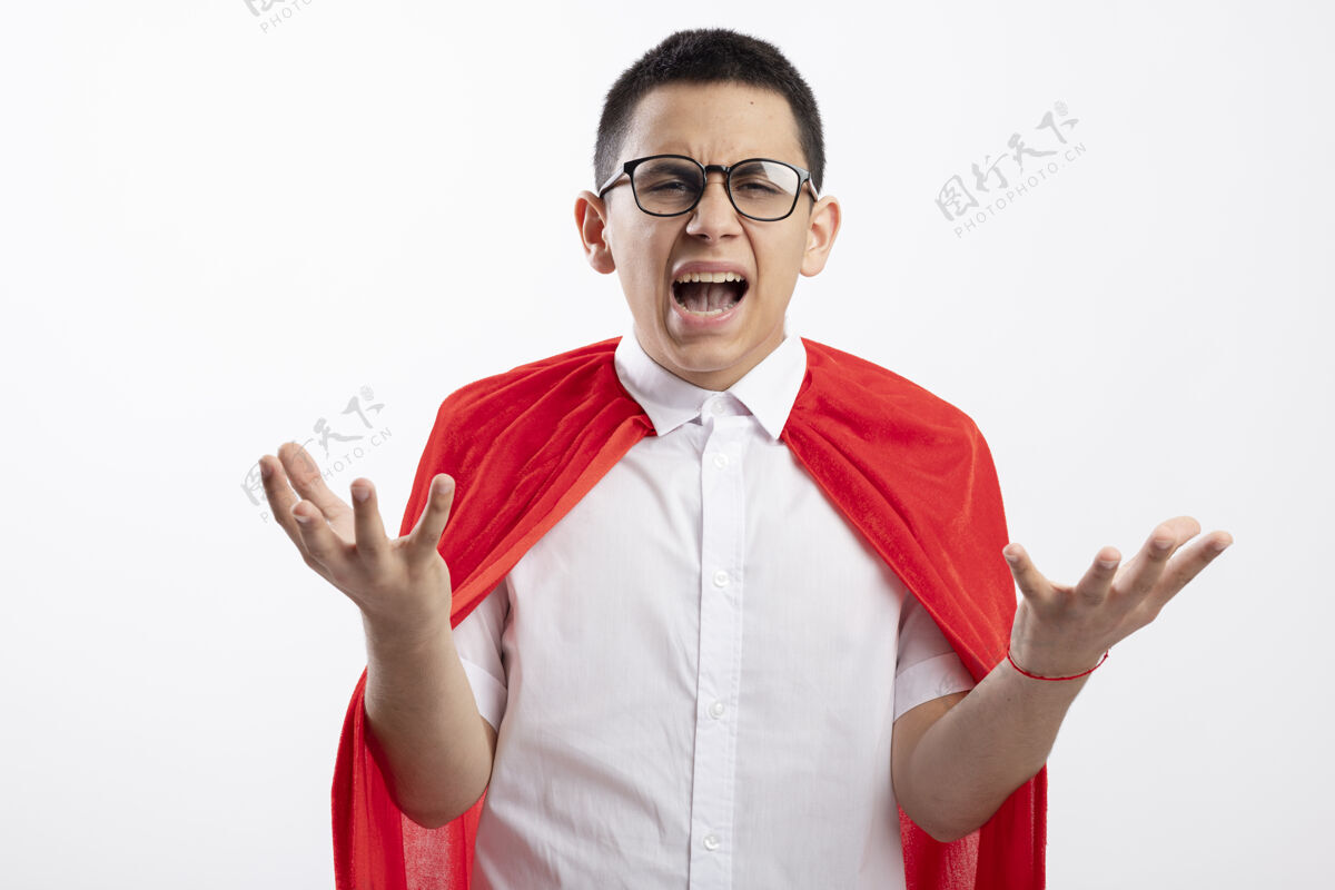 斗篷愤怒的年轻超级英雄男孩穿着红色斗篷 戴着眼镜 看着镜头 在白色背景上孤立着空空的双手年轻红色空