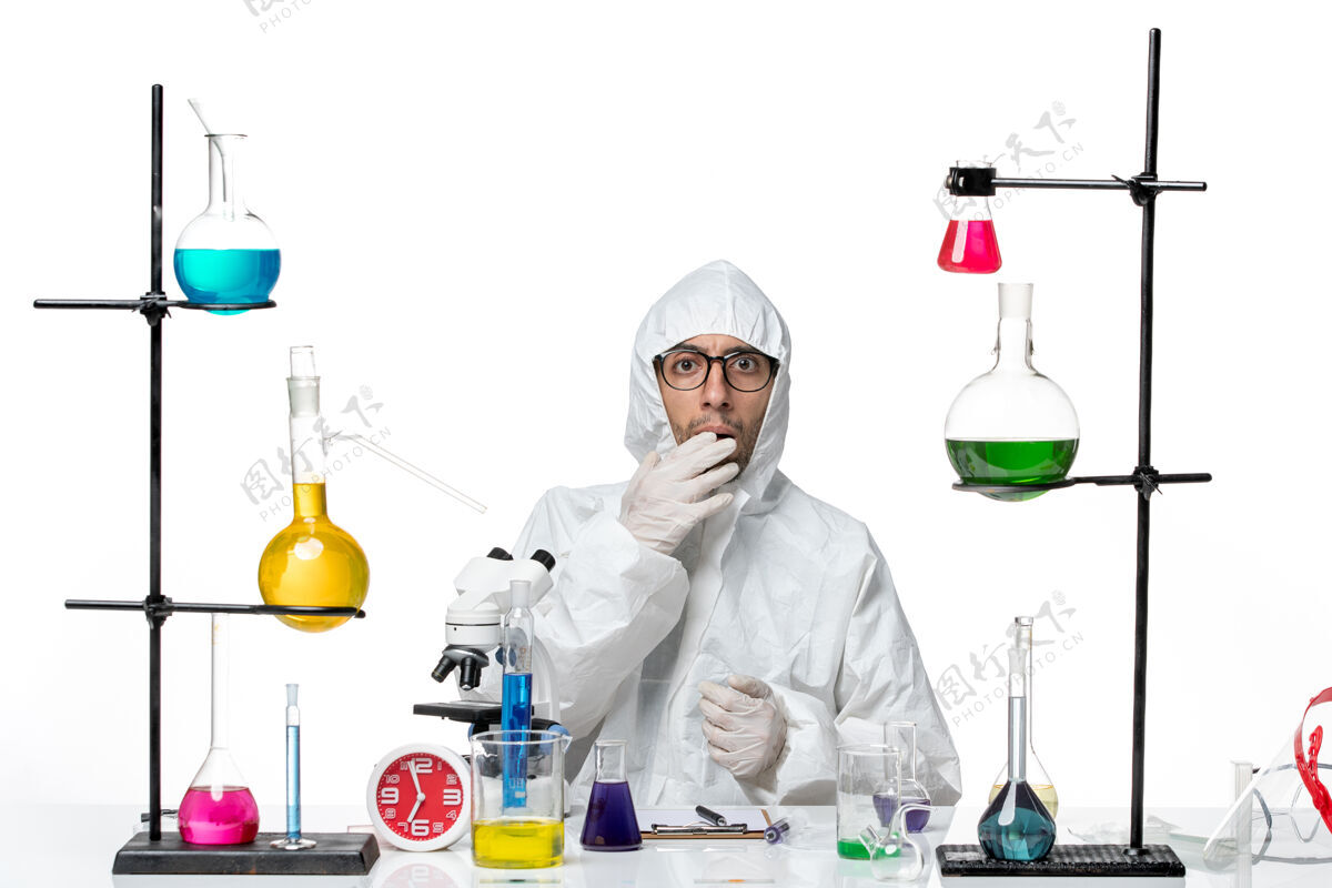 化学正面图穿着特殊防护服的男科学家围坐在办公桌旁 拿着解决方案科学实验室视图