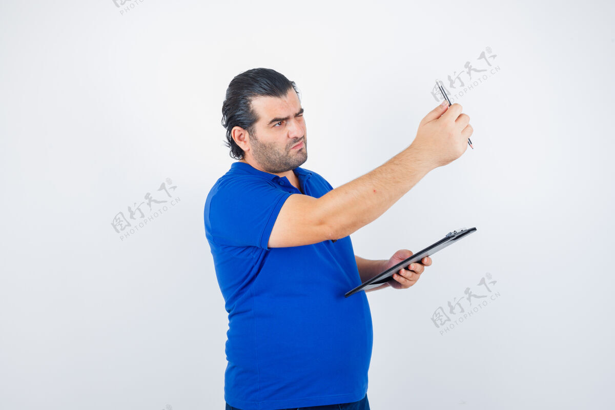 游戏中年男子穿着马球衫拿着剪贴板 看着铅笔 目光集中前视图前面互联网商务