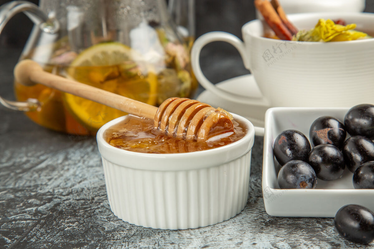 杯子前视图甜甜的蜂蜜茶和橄榄在黑暗的表面早餐咖啡橄榄