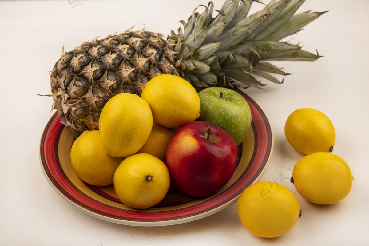 人多汁水果的俯视图 如菠萝 五颜六色的苹果和柠檬放在一个碗里 柠檬被隔离在白色的墙上膳食农业顶部