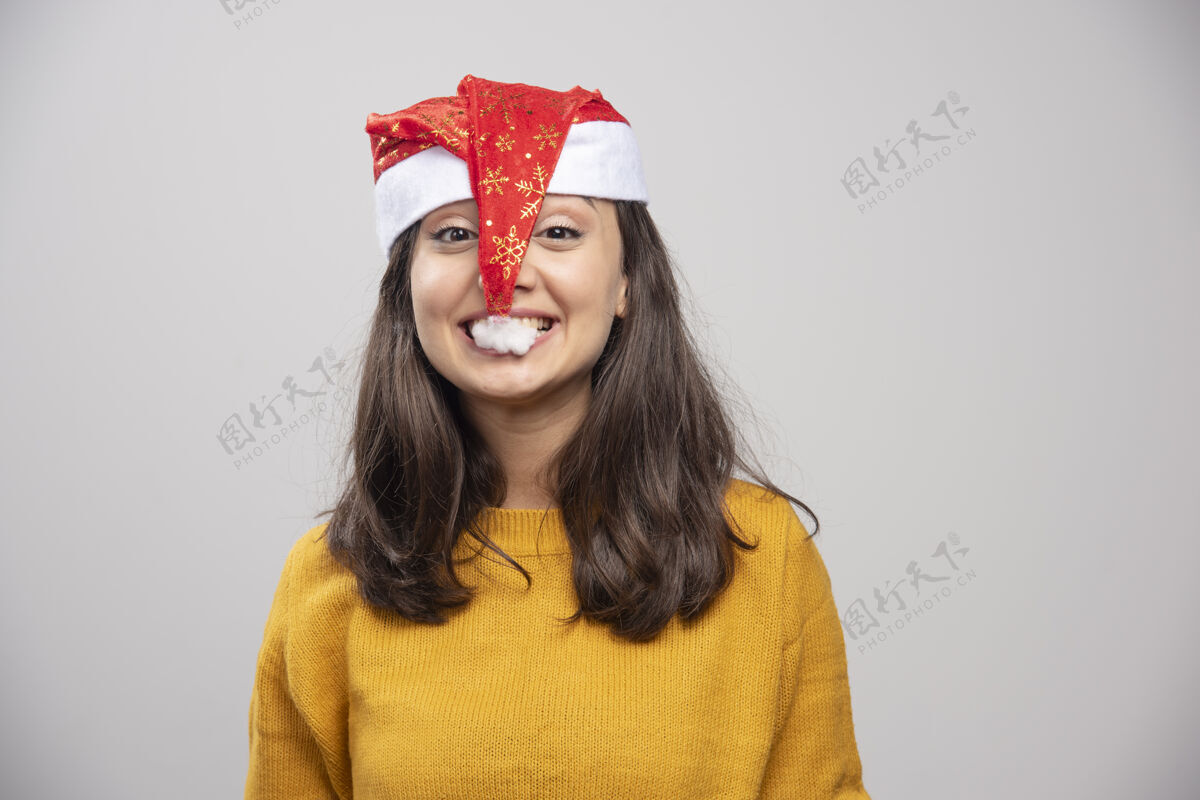 礼品盒年轻的女人想吃掉圣诞老人的红帽子圣诞节女模型
