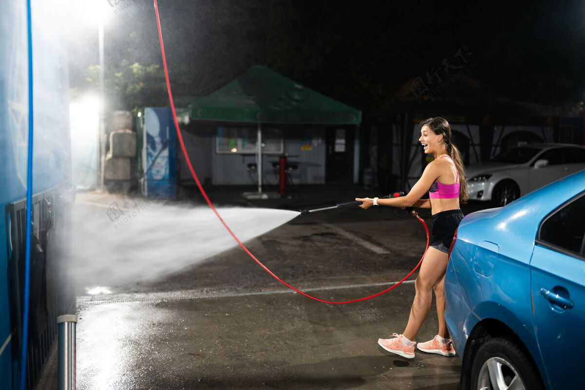 洗一个年轻女子在洗车场洗一辆蓝色的车肖像人乐趣
