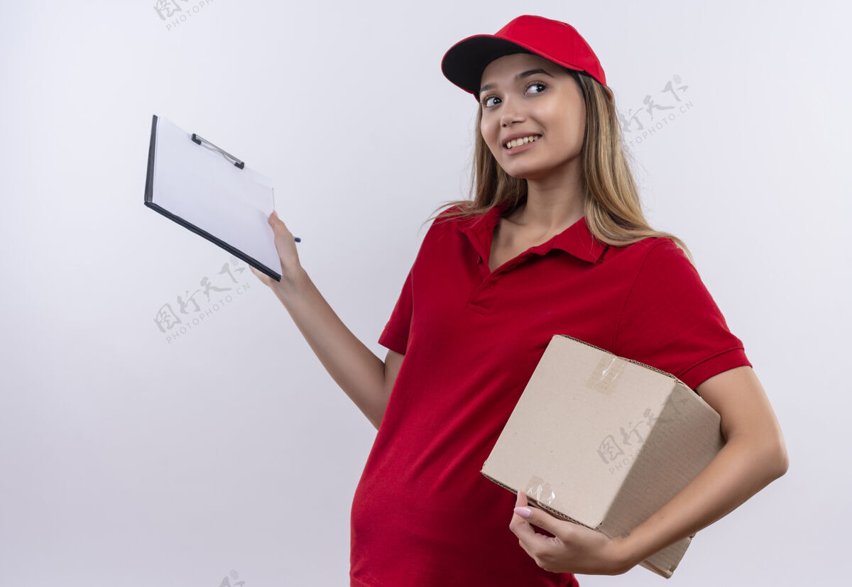 帽子看着身边喜气洋洋的送外卖的小女孩 穿着红色制服 戴着帽子 拿着盒子和剪贴板隔离在白色的墙上请穿壁板剪贴板