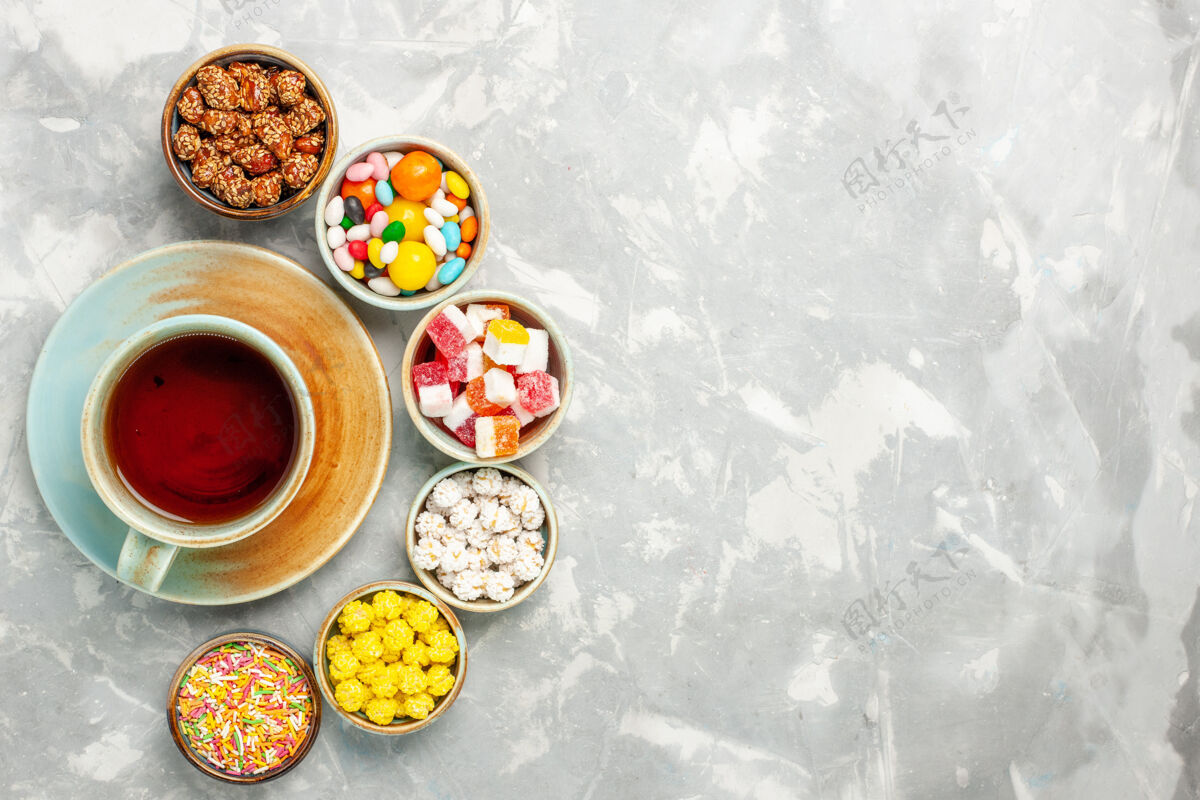 早餐白色表面上有棉花糖和茶的不同甜糖果的俯视图茶小吃食物