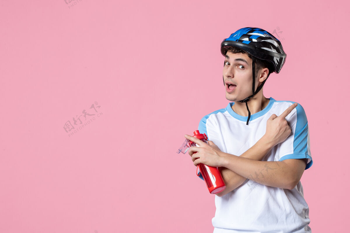 男人前视图穿着运动服 戴着头盔 拿着一瓶水的年轻运动员运动瓶子前面