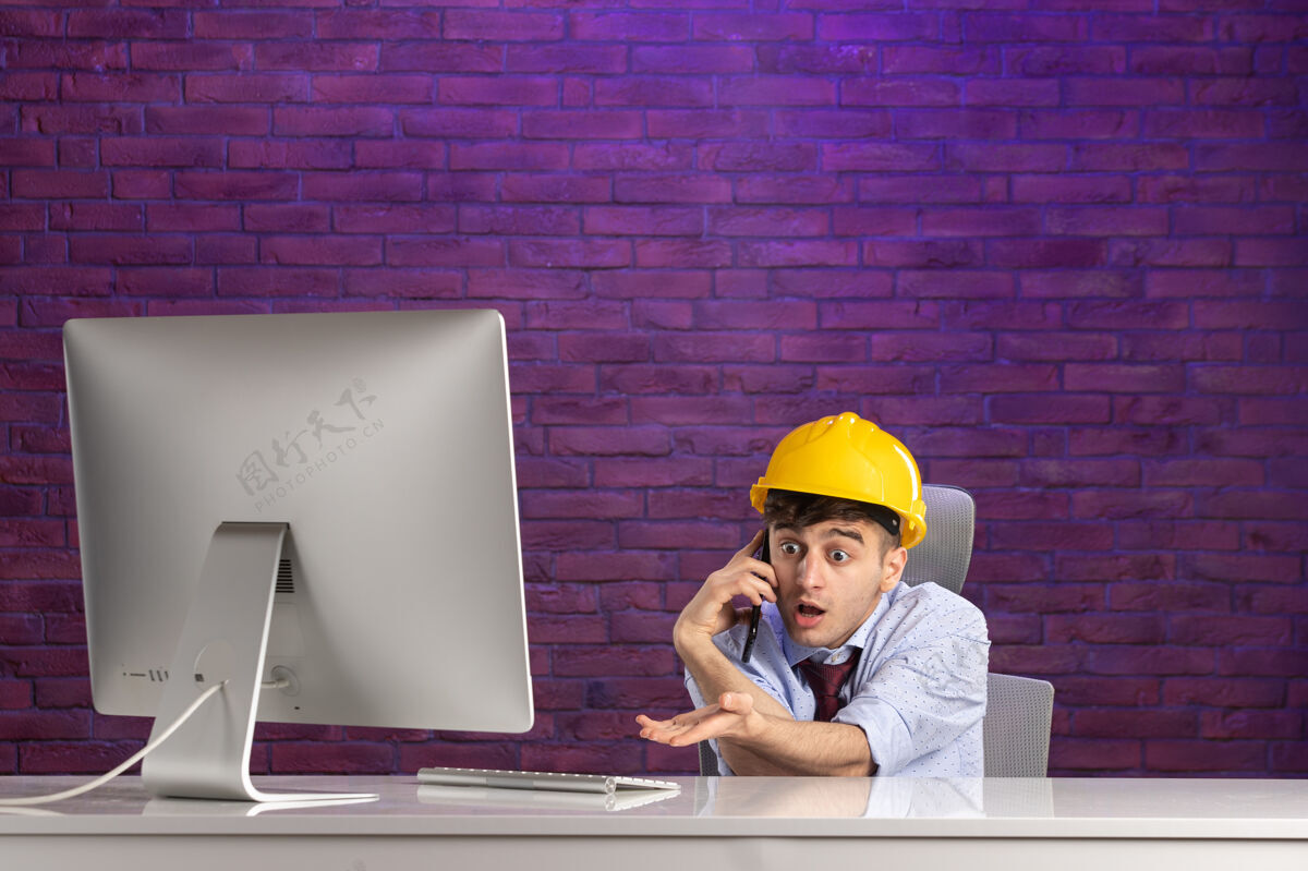 工作正面图：男施工员在办公桌后面打电话建筑办公桌工程师