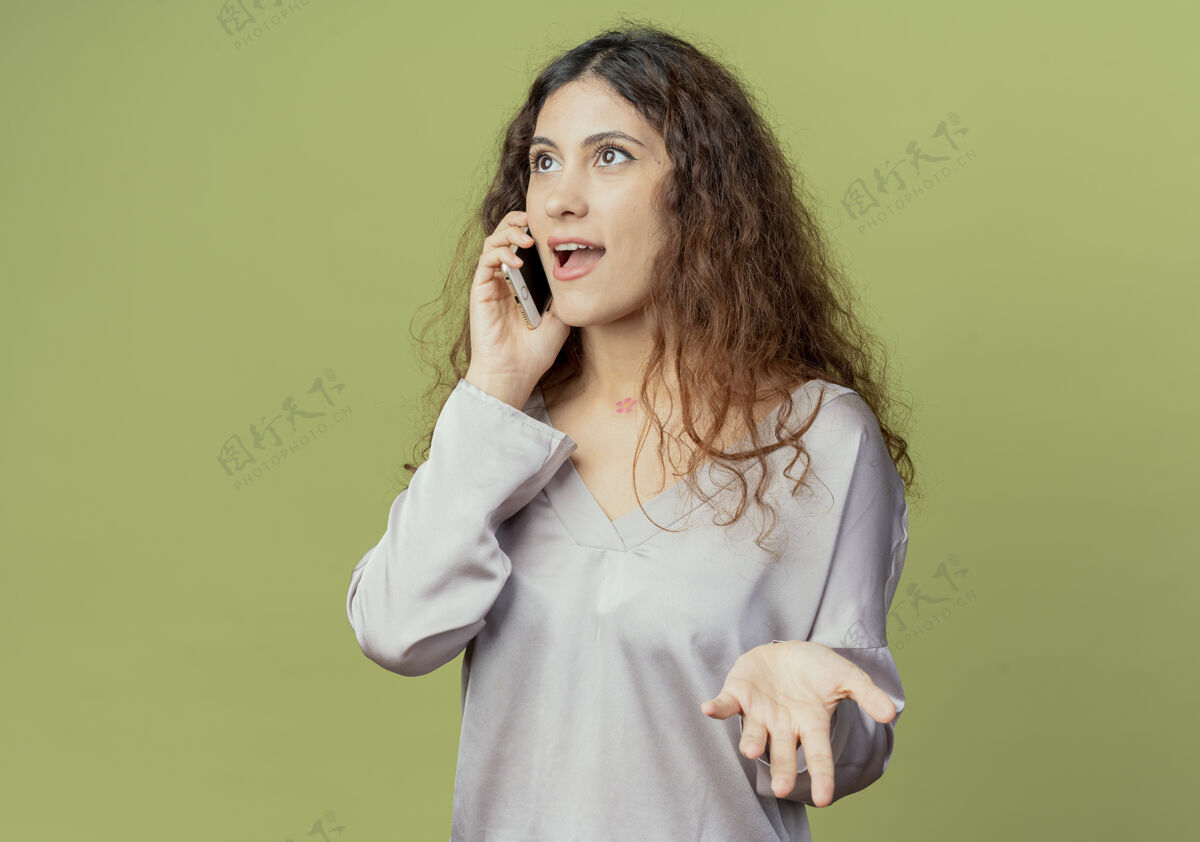 请看着一旁高兴的年轻漂亮女上班族讲电话摊开手孤立在橄榄绿的墙上工人侧线橄榄