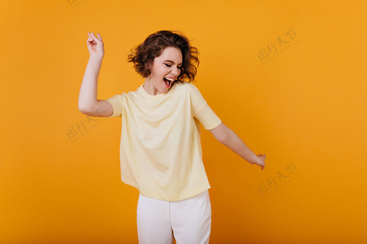 肖像浅棕色头发的女孩穿着黄色t恤跳舞 充满灵感的面部表情活跃的年轻女子穿着休闲夏装 在室内玩得很开心运动舞蹈积极