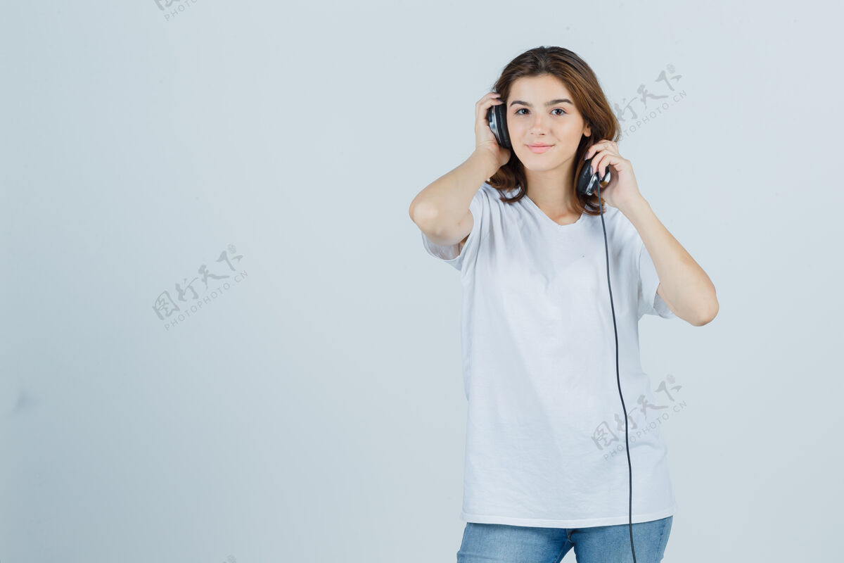 卷发穿着白色t恤 牛仔裤的年轻女性摘下耳机 看起来很梦幻 前视图漂亮惊喜模型