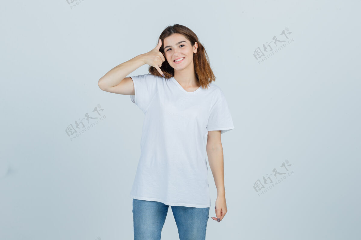 魅力穿着t恤和牛仔裤的年轻女士 展示着打电话的姿势 看上去很快乐 正前方的景色微笑人亚洲人