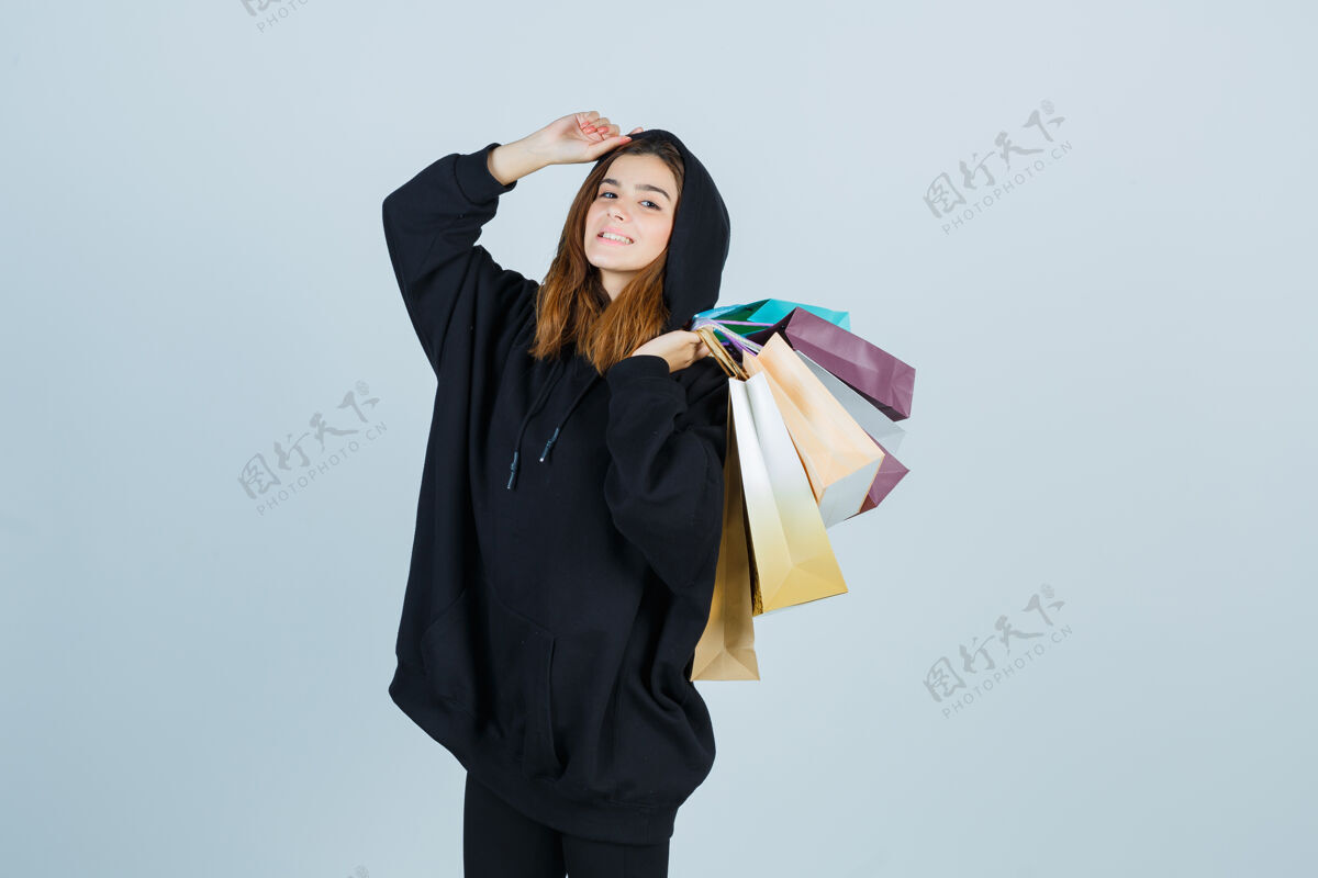黑发年轻的女士肩上拿着包 穿着超大的连帽衫 裤子 看起来很有吸引力 正面视图皮肤健康年轻